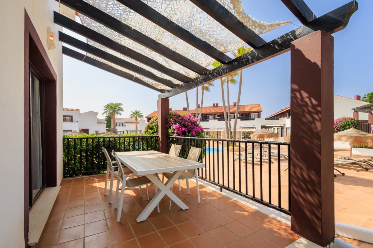 Terraza del duplex con mesa y sillas frente a la piscina