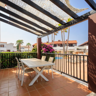 Terraza del duplex con mesa y sillas frente a la piscina