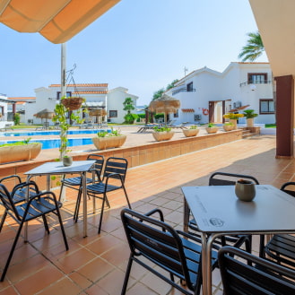 Bar con terraza y mesas frente a la piscina