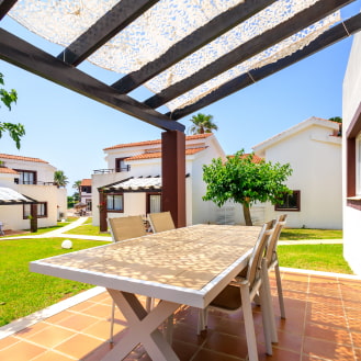 Terraza con mesa bajo pérgola en jardín 