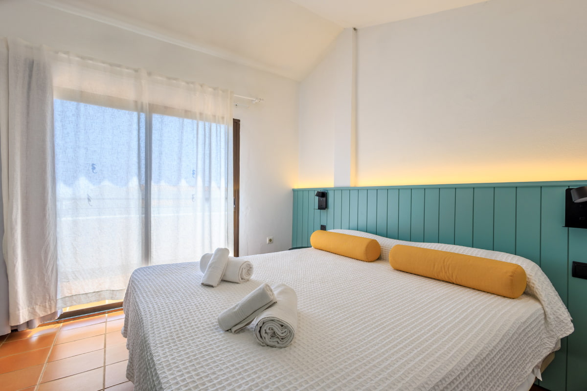 Dormitorio luminoso con cama doble y cabecero verde