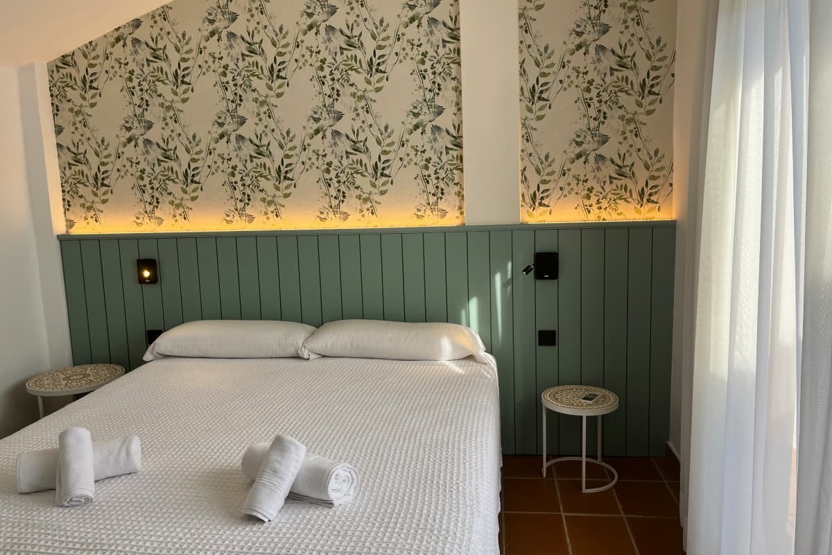 Dormitorio con papel pintado floral y cama doble