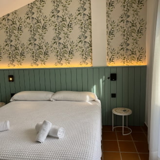 Dormitorio con papel pintado floral y cama doble