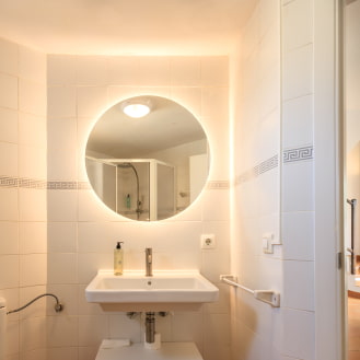 Baño moderno con espejo redondo y ducha