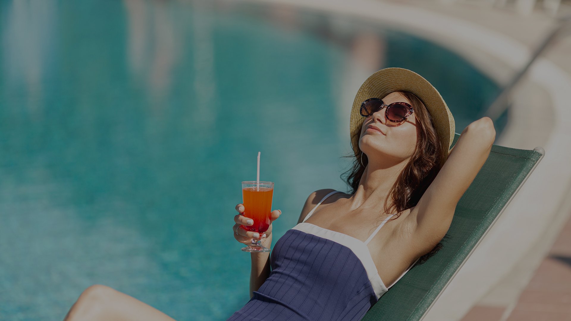 Mujer disfrutando de un cocktail junto a la piscina